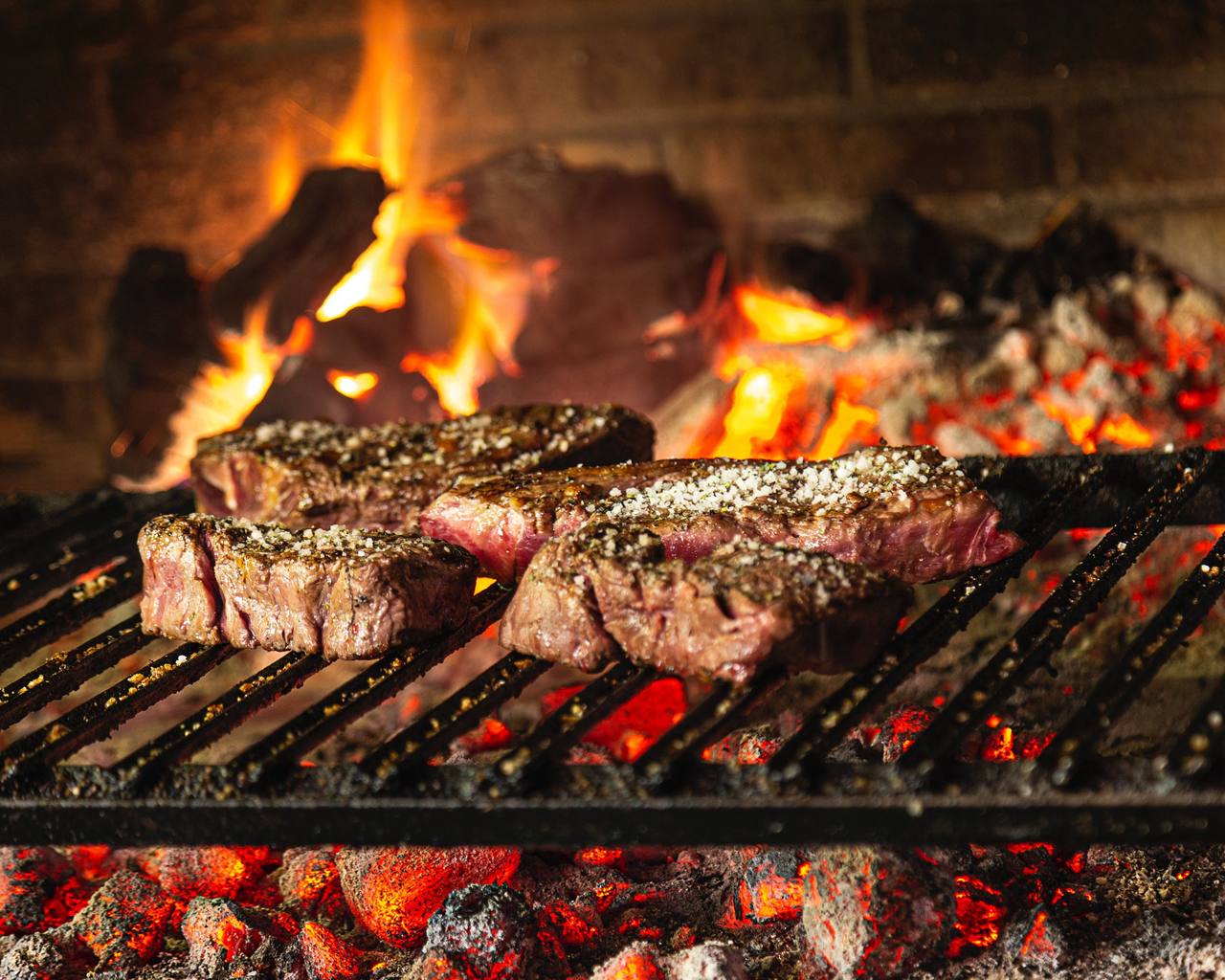 Steaks braaing over hardwood coals